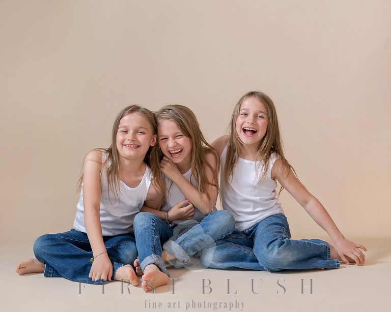 Triplet sisters laughing while being photographed by Suzanne Taylor Photography in Calgary Alberta.