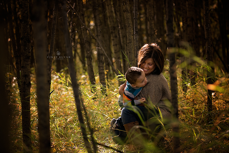 Mom and son sitting in the woods together on the ground