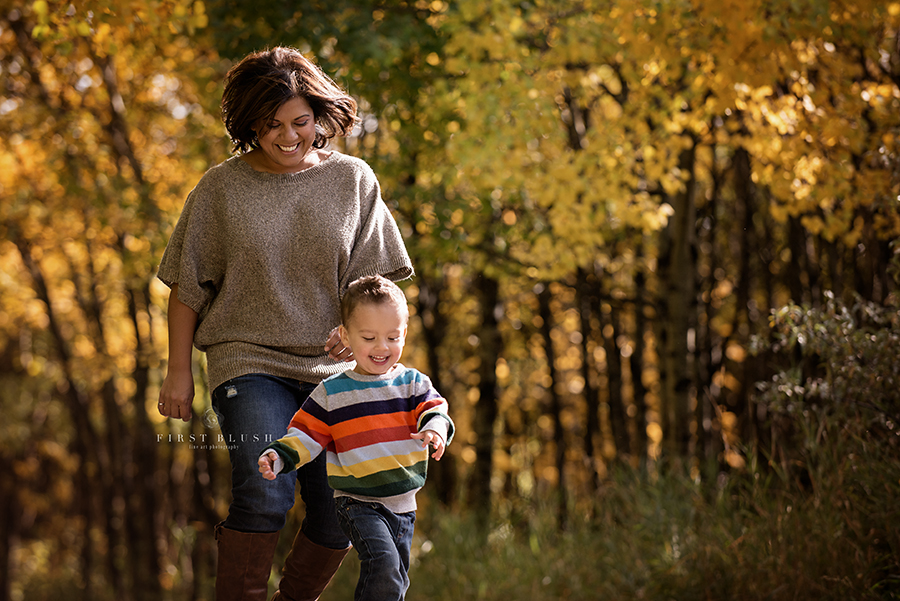 A mom and her toddler son run down a path.