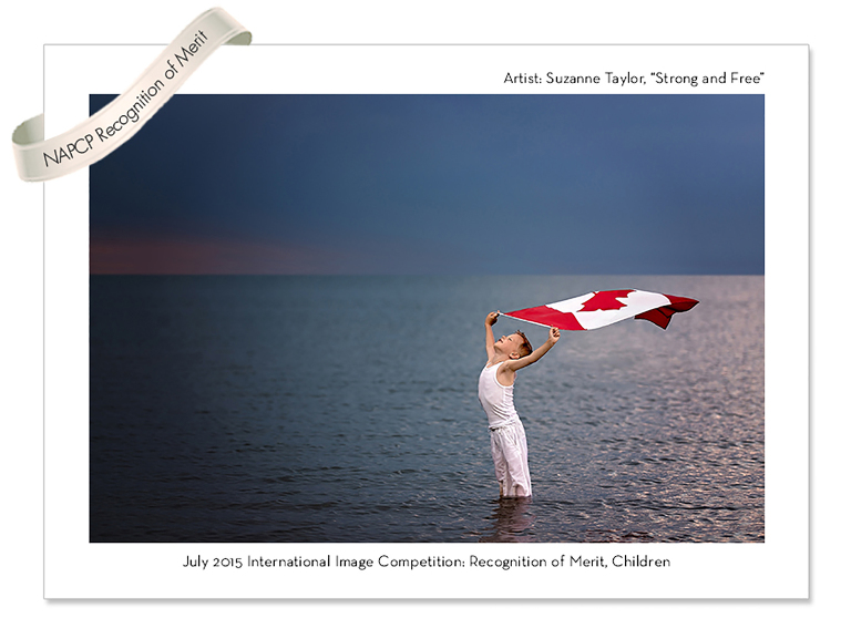 Young boy dressed in white holding the Canada Flag above his head with the wind blowing it