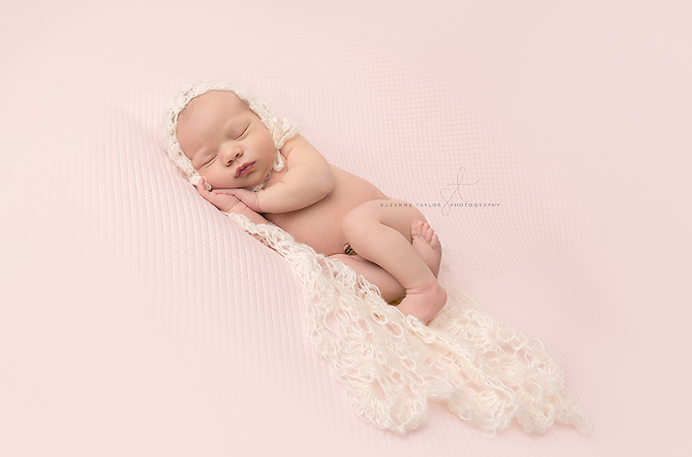 Newborn girl Everly laying on a pink blanket sleeping