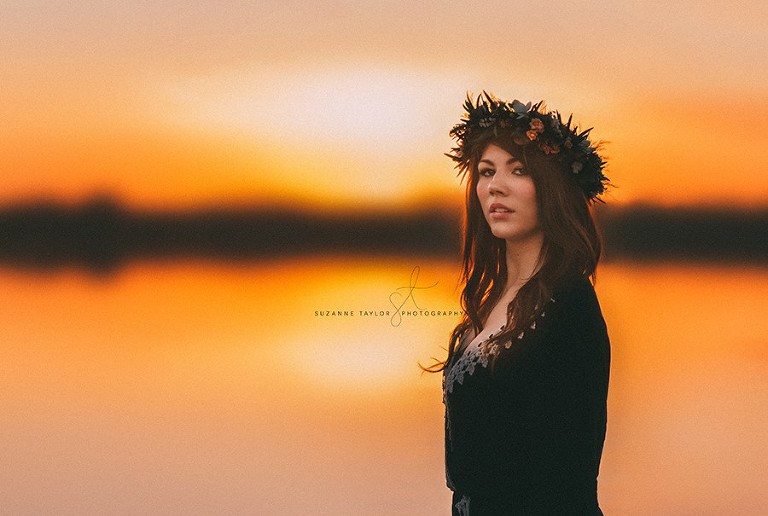 High school senior with floral crown standing at sunset looking at the camera at Gull Lake, Alberta