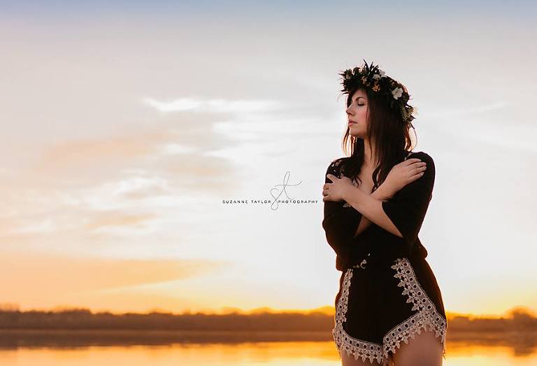 High school senior standing with arms crossed and eyes closed at sunset at Gull Lake, Alberta