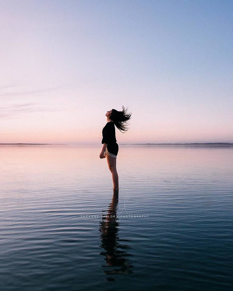 High school senior standing in Gull Lake, AB tossing her hair back during blue light time of day