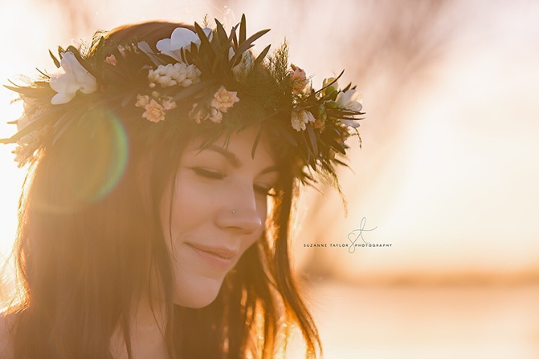 A high school senior smiles at sunset with her eyes closed