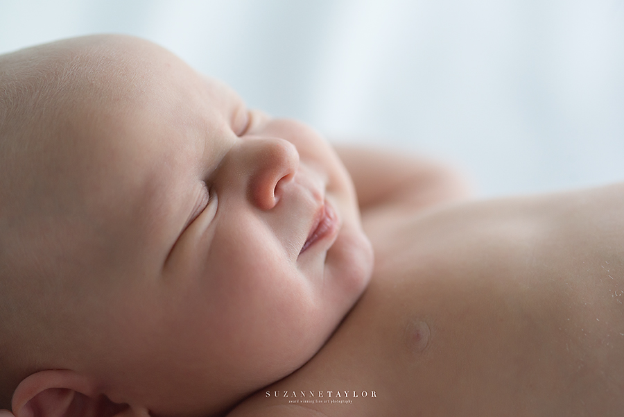 A close up side profile of a newborn twin resting and smiling