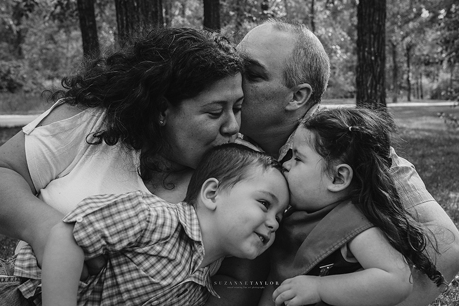 A family embraces each other and kisses each other heads in Calgary, Alberta sharing love.