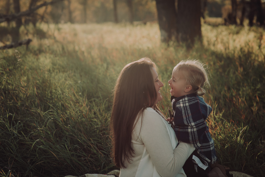 Red Deer Photographer Suzanne Taylor sits in the grass of Calgary, Alberta with her oldest triplet.