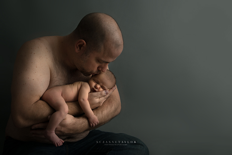 Calgary Newborn is held in his fathers arms by Suzanne Taylor Photography