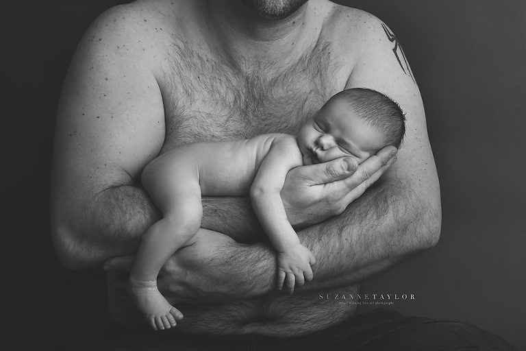 Calgary Newborn is held in his fathers arms by Suzanne Taylor Photography